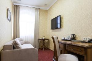 West Park Hotel في كييف: غرفة في الفندق مع أريكة ومكتب وتلفزيون