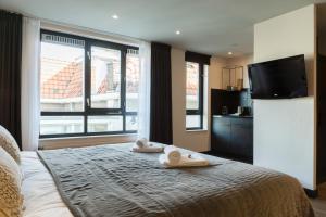 a bedroom with a bed with towels and a flat screen tv at Boutique Suites Lisse - Schiphol in Lisse