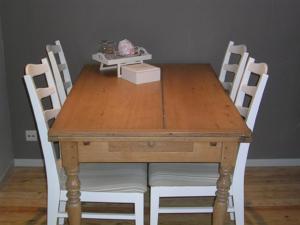 een houten tafel met vier stoelen en een doos erop bij Bed & Breakfast Esprit de Mer in De Panne