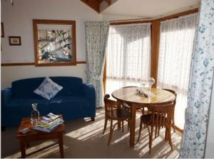 a living room with a blue couch and a table at Cottages on Edward in Deniliquin