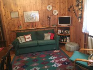 a living room with a green couch and a television at Casa Alagna in Alagna Valsesia