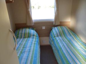 two beds in a small room with a window at Chalet in Wilbertoord