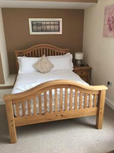 1 dormitorio con cama de madera con sábanas y almohadas blancas en The Waverley Guest House, en Inverness