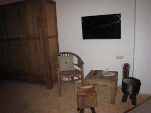 a room with a chair and a table and a television at Pension Schihütte in Oberstaufen