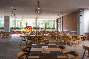 a restaurant with wooden tables and chairs and windows at Hotel Arpezos in Kŭrdzhali