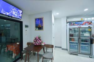a restaurant with a table and chairs and a refrigerator at Jarat Mansion in Surin