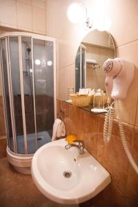 a bathroom with a sink and a shower and a blow dryer at Kupecheskiy Club Hotel in Bor