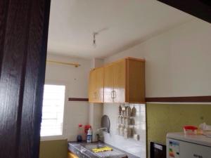 uma cozinha com armários de madeira e um frigorífico em Cozy Appartement em Douar Ben Chellal
