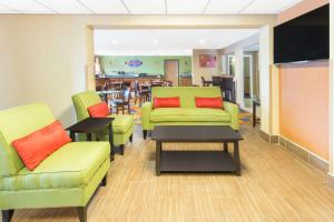 a waiting room with green chairs and tables and a television at Baymont by Wyndham Waukesha in Waukesha