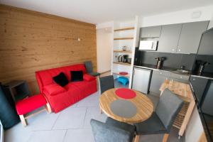 salon z czerwoną kanapą i stołem w obiekcie Terres de France - Résidence les Silènes w mieście Allevard