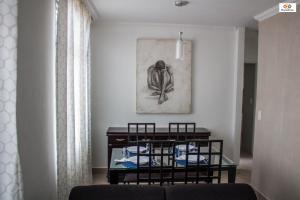 4let BH Del Rey في بيلو هوريزونتي: غرفة معيشة مع طاولة وصورة على الحائط