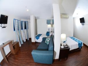 a room with two beds and a couch and a tv at Skyblue Hotel in Cebu City