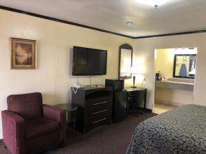ein Hotelzimmer mit einem Bett, einem Stuhl und einem TV in der Unterkunft Flamingo Inn in Elk City