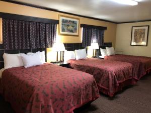 two beds in a hotel room with red sheets at Flamingo Inn in Elk City