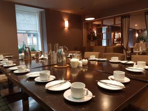 a long table with cups and saucers on it at Fairburn Hotel in Mauchline