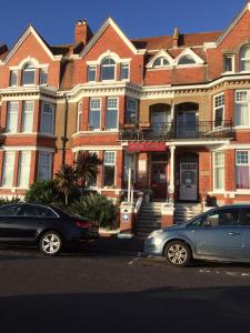 two cars parked in front of a large brick building at Arun Sands Rooms in Littlehampton