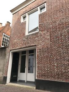 ミデルブルフにあるMooi Genieten Studioの白いドアと窓のあるレンガ造りの建物
