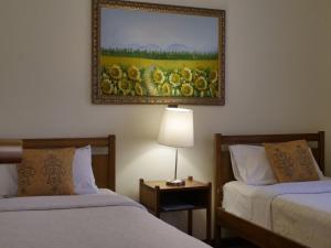 two beds in a hotel room with a picture on the wall at Hotel La Fuente in Coquimbo