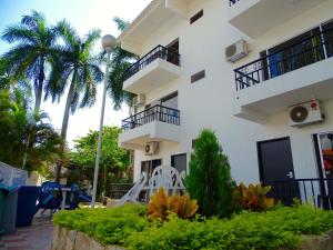 a white building with palm trees in front of it at Alborada Hotel Melgar in Melgar