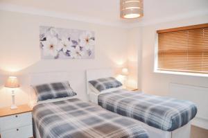 two beds in a white room with a window at Blackwater Meadow Apartment in Ellesmere