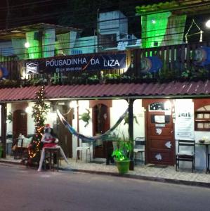 a person sitting in front of a restaurant at night at Pousadinha da Liza in Mangaratiba