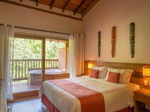 a bedroom with a bed and a balcony with a tub at Kalango Hotel Boutique in Ilhabela