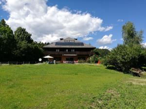 ein großes Haus mit einem grünen Feld davor in der Unterkunft Villa Leone in Maria Rain