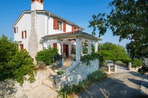 a white house with a palm tree in front of it at Villa Primela**** in Labin