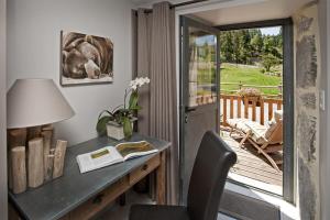 a home office with a desk and a view of a deck at Hôtel Les Granges de Bigose in Rimeize