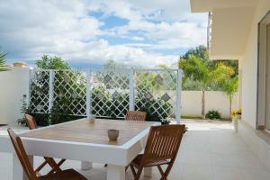 een tafel en stoelen op een patio met een hek bij Bosco Sea Apartments in San Leone
