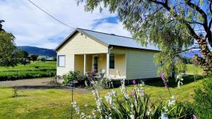 a small yellow house in a field with flowers at The Manager's Cottage in Grove