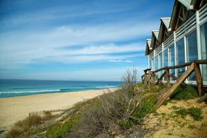 a building on the beach next to a sandy beach at Casinha da Aldeia in Melides