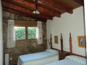 a bedroom with two beds and a stone wall at Casas Rurales Ribera de Salobre in Salobre