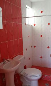 a red and white bathroom with a toilet and a sink at Departamento vista al mar in Ilo
