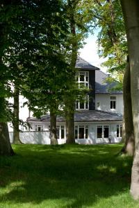 une maison blanche avec des arbres devant elle dans l'établissement Hotel Bess, à Albersdorf