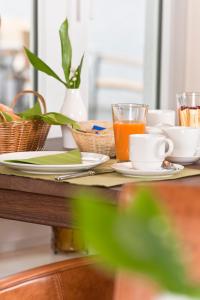 a table with plates and cups and a glass of orange juice at Hotel Bess in Albersdorf