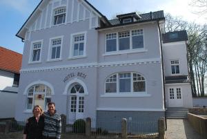 two people standing in front of a white house at Hotel Bess in Albersdorf