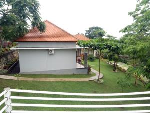 a white house with a fence next to a yard at 3D Homestay in Uluwatu