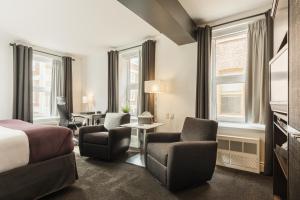 ein Hotelzimmer mit einem Bett, Stühlen und Fenstern in der Unterkunft Hôtel des Coutellier in Québec