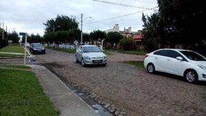 two cars parked on a dirt road next to a street at Casa 3 dormitórios in Tramandaí
