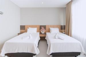 2 letti in camera d'albergo con lenzuola bianche di Mogens Guesthouse a Bandung