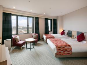 a hotel room with two beds and a table and chairs at HOTEL MYSTAYS PREMIER Narita in Narita +93 photos