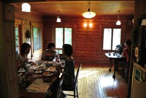 um grupo de pessoas sentadas numa mesa numa cabana em Polan no Fue em Minamioguni