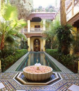 einen Pool in der Mitte eines Gebäudes mit einem Brunnen in der Unterkunft Riyad Al Moussika in Marrakesch