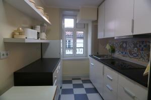 a kitchen with white cabinets and a black counter top at Baixa Apartamento in Bragança +7 photos