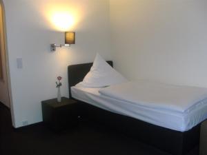 Dormitorio pequeño con cama con almohada blanca en Waldhotel Tropfsteinhöhle en Wiehl