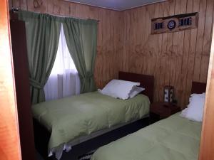 two beds in a room with a window at Agroturismo los Colihues 2 in Castro