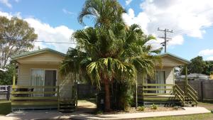 a house with a palm tree in front of it at Bushchooks Travellers Village in Bororen