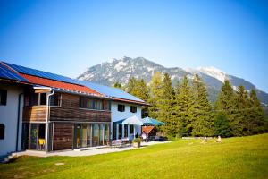 a house with mountains in the background with a yard at Jugendherberge Mittenwald in Mittenwald