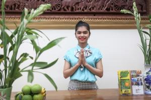 Angkor Udom Guesthouse في سيام ريب: امرأة تقف أمام طاولة بيديها في الأمام